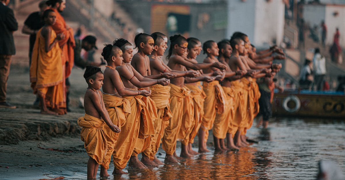 A group of young monks in orange robes perform a ritual by the Ganges River in Varanasi, India.
